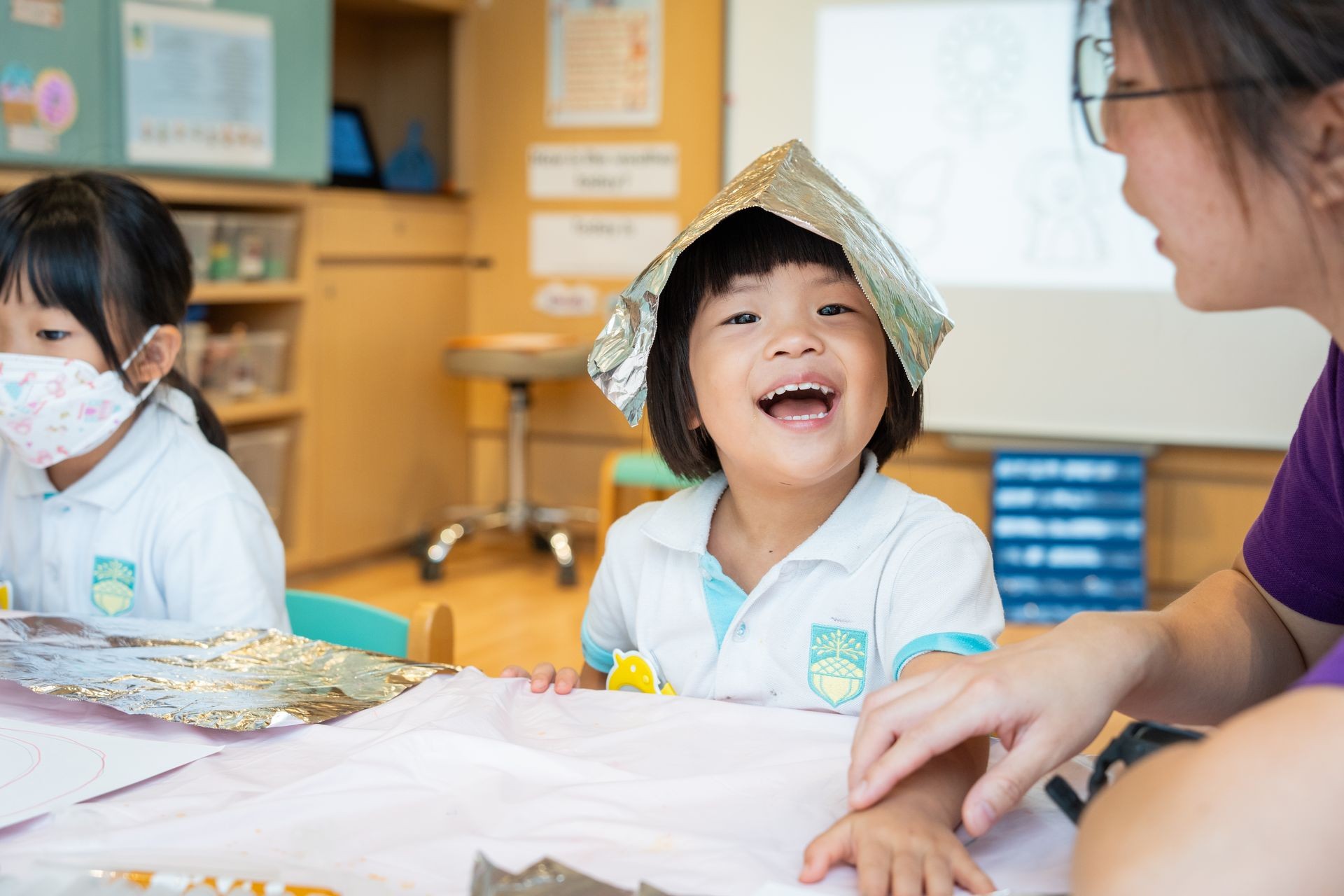 Girl in Mighty Oaks uniform laughing with foil on her head — joyful early learning